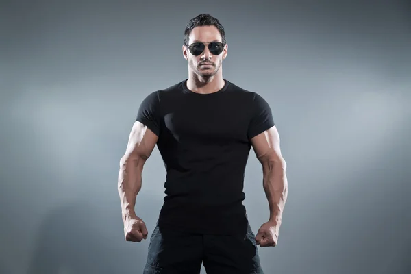 Combat muscled action hero man wearing black t-shirt with pants — Stock Photo, Image