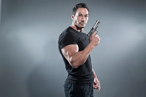 액션 영웅 벌인 남자는 총을 들고. 블랙 t-셔츠를 착용 하 고 스톡 이미지