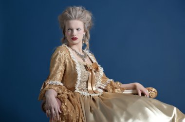 Retro baroque fashion woman wearing gold dress. Sitting on vinta