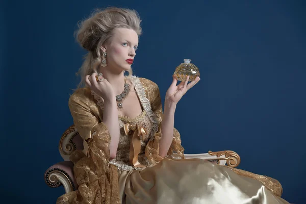 Retro baroque fashion woman wearing gold dress. Holding bottle o — Stock Photo, Image