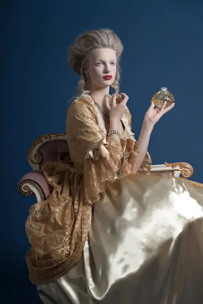 Retro baroque fashion woman wearing gold dress. Holding bottle o — Stock Photo, Image