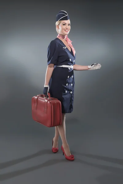 Lächelnde retro-blonde Stewardess im blauen Anzug. mit rotem l — Stockfoto