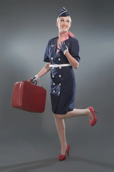Улыбающаяся ретро-блондинка стюардесса в синем костюме. Холдинг красный л — стоковое фото