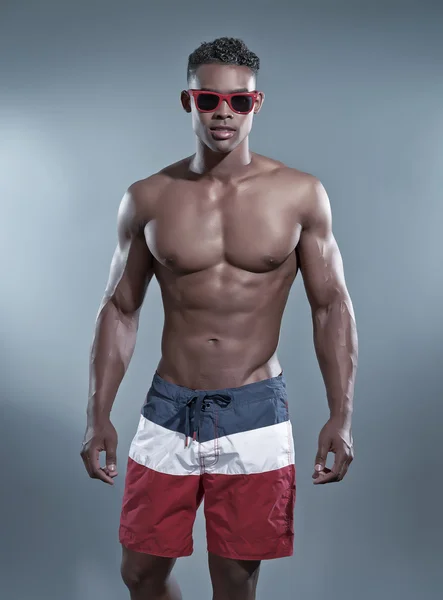 Fitness Schwarzafrikaner trägt gestreifte Shorts und rote Sonnenbrille — Stockfoto