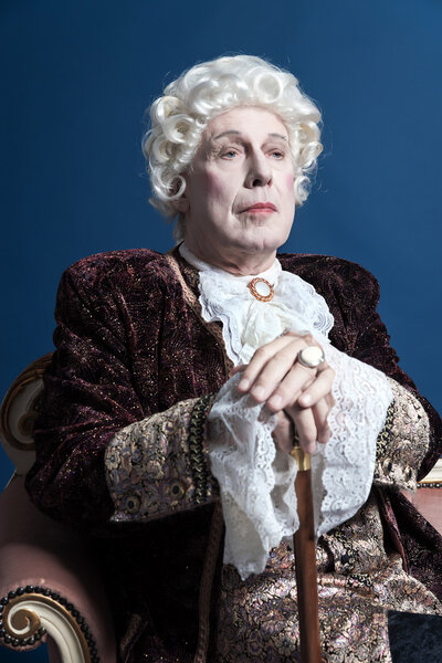 Человек в стиле ретро в белом парике с тростью в руках
