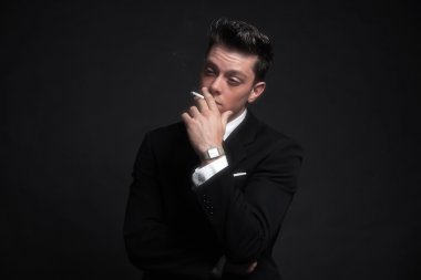 retro ellili moda adam sigara içiyorum. siyah sui giyiyor