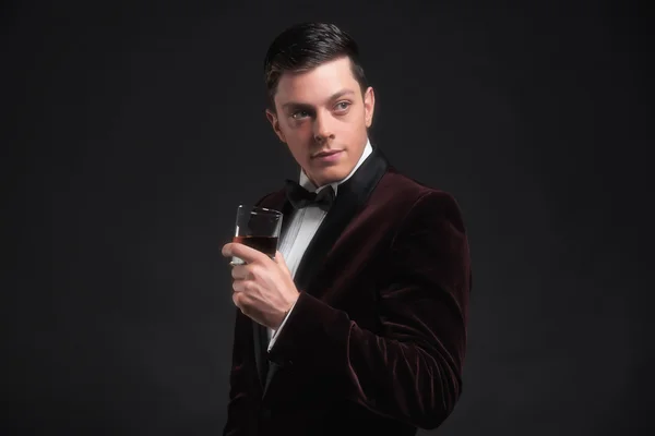 Hombre de negocios bien vestido y guapo sosteniendo un vaso de whisky . —  Fotos de Stock