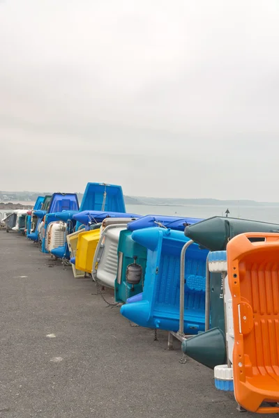 Row of colorful plastic boats on shore. Cloudy sky. Brittany. Fr — Stock Photo, Image