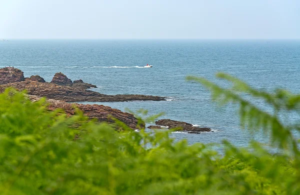 Costa rocosa con lancha rápida en el horizonte . —  Fotos de Stock