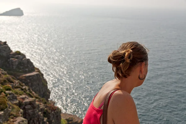 Vrouwelijke toeristische kijken naar de oceaan van klif. over de schouder — Stockfoto