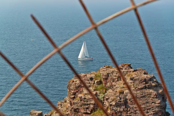 White sailing boat seen through iron fence. — Stock Photo, Image