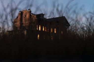 Eerie dilapidated historic manor with illuminated windows at dawn. 3D render.