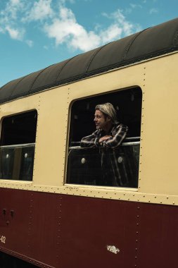 Sakallı sarışın bir adam klasik tren kompartımanından dışarı bakıyor. Platformdan görüntülendi.