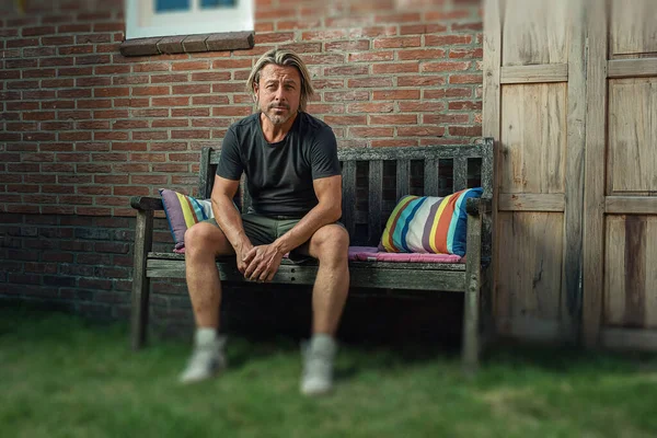 Blond Man Black Shirt Green Shorts White Sneakers Sits Bench — Stockfoto