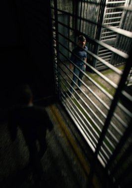Prison guard walks towards prisoner who is behind bars. 3D render.