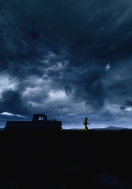 Adam karanlık bir gökyüzünün altında kırsal alanda ışıklı farları olan klasik bir pikaptan kaçıyor. 3 Boyutlu Hazırlama.