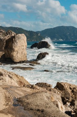 Mavi bulutlu gökyüzünün altında köpüklü dalgalar.