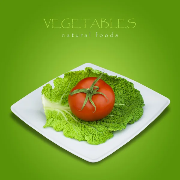 Savooikool en tomaat in plaat op groene achtergrond — Stockfoto