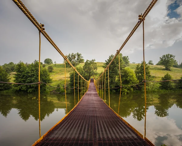 Ponte sospeso in metallo sul fiume — Foto Stock