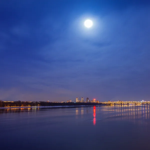 Mond über dem Fluss bei der Winterstadt — Stockfoto