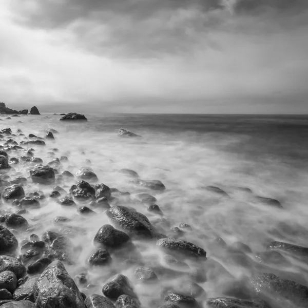 Uma paisagem marinha minimalista. Longa exposição de mar e rochas. Preto e branco . — Fotografia de Stock