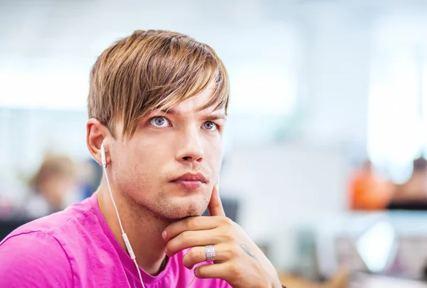 Porträt eines gutaussehenden jungen Mannes, der mit Kopfhörern Musik hört — Stockfoto