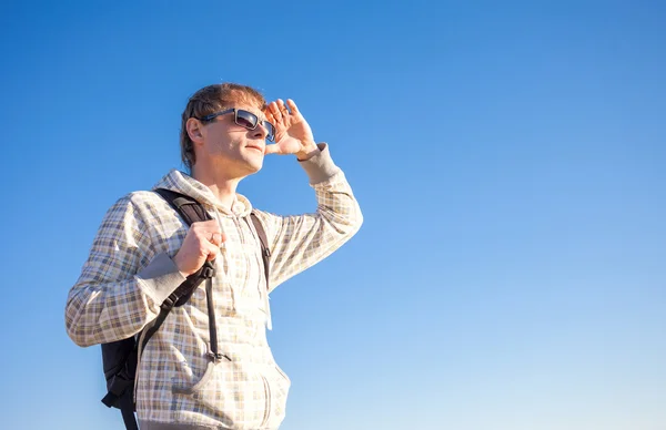 Uomo felice escursionista tenendo lo zaino in una giornata di sole contro un cielo blu — Foto Stock