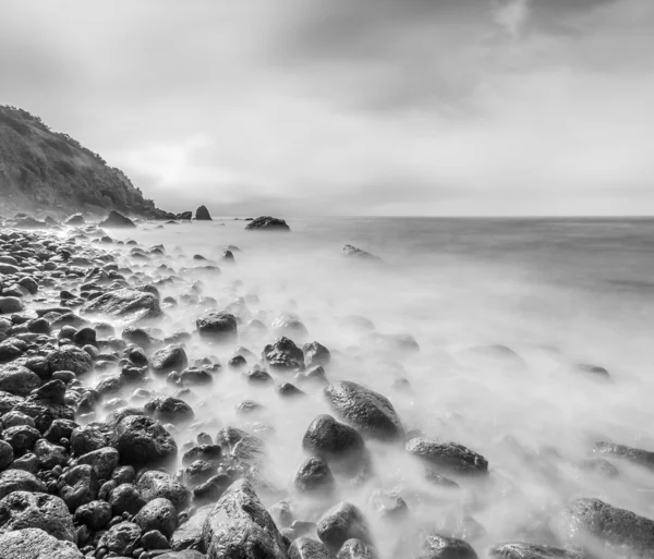 Minimalist seascape. Long exposure of sea and rocks. Black and white.