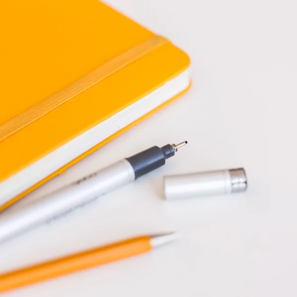 Gula omslag anteckningsboken med svart penna och litet skärpedjup — Stockfoto