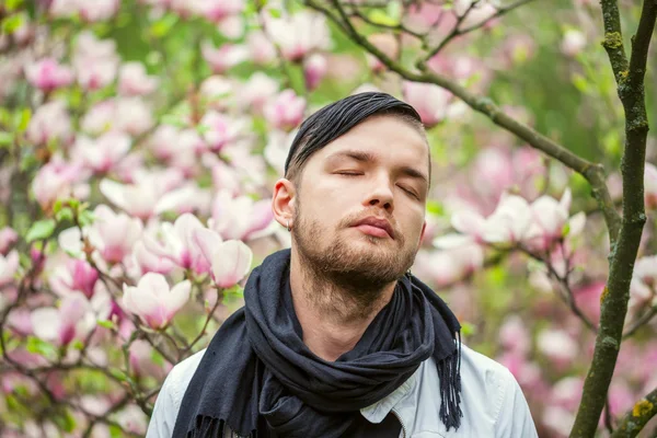 Portret van jonge mooie modieuze man in de bloemrijke tuin — Stockfoto