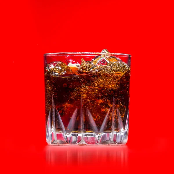 Verre avec éclaboussure de whisky sur fond rouge — Photo