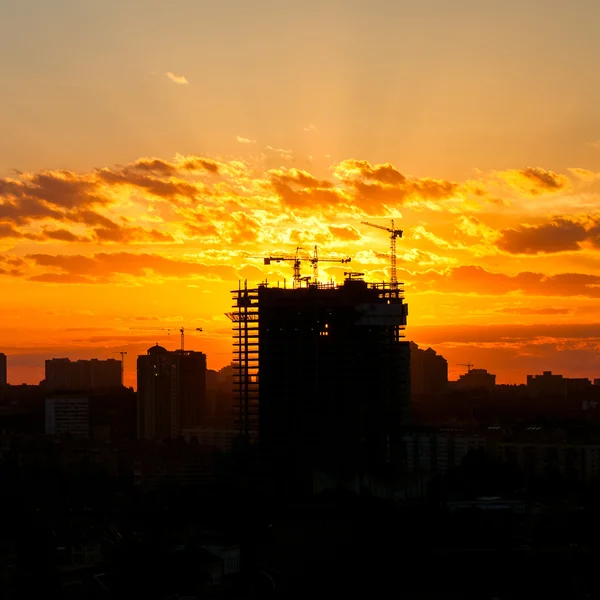 Silhouette of the tower crane on the construction site with city building background — Stock Photo, Image