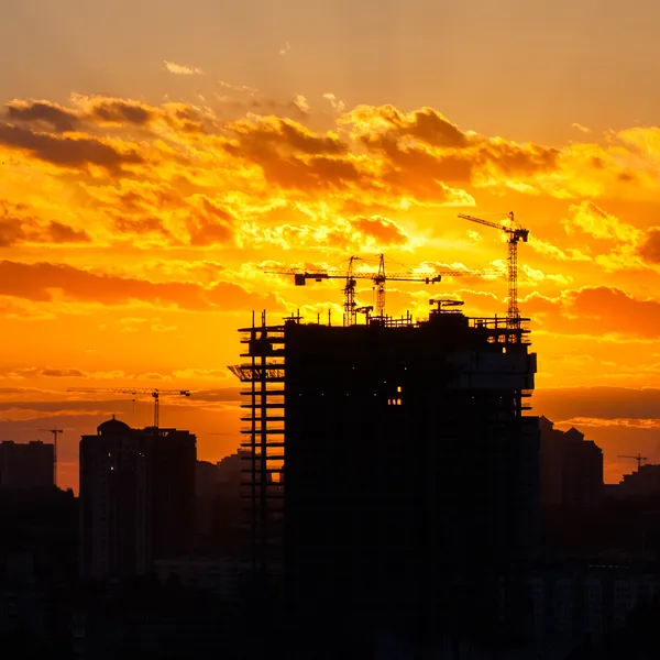 Silhouette della gru a torre sul cantiere con sfondo edilizio della città — Foto Stock