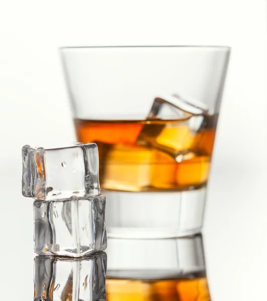 Glass of whiskey with ice, isolated on white background and small depth of field — Stock Photo, Image