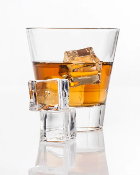 Glass of whiskey with ice, isolated on white background and small depth of field — Stock Photo, Image