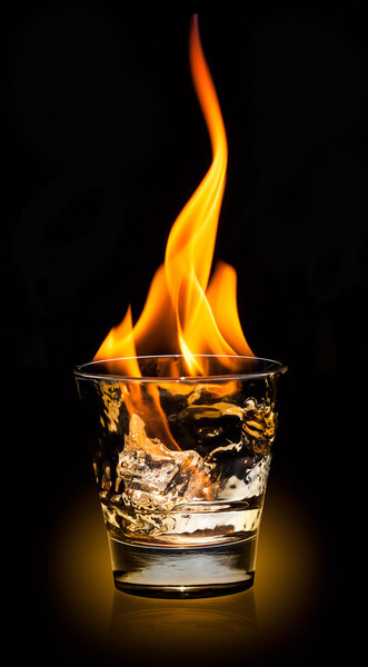 Glass with whiskey splash and fire on black background