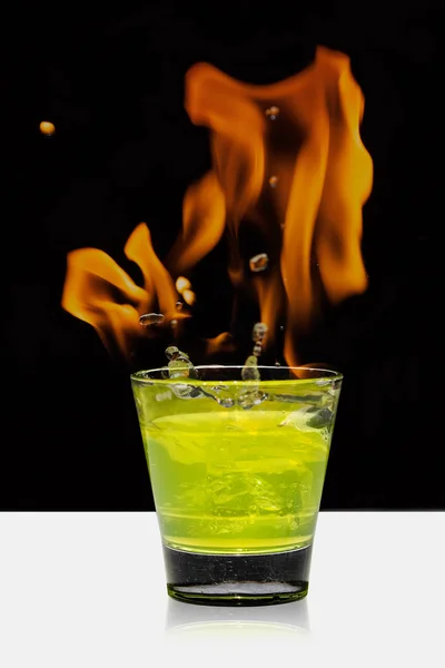 Glass with mojito splash and fire on black background — Stock Photo, Image