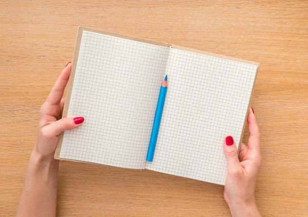 Women hand holding new notebook on wooden background — Stock Photo, Image