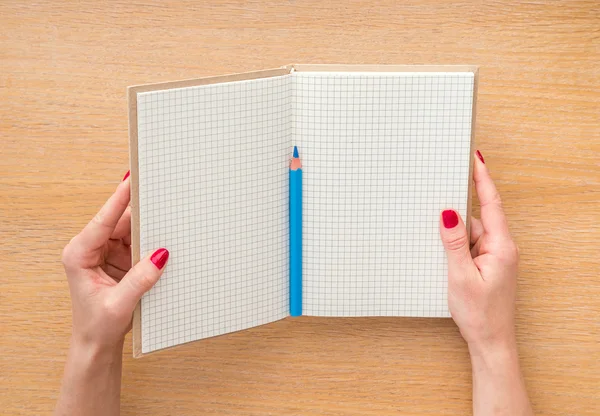 Mano de las mujeres sosteniendo nuevo cuaderno sobre fondo de madera — Foto de Stock