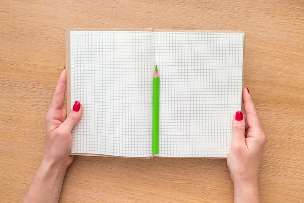 Mano de las mujeres sosteniendo nuevo cuaderno sobre fondo de madera —  Fotos de Stock