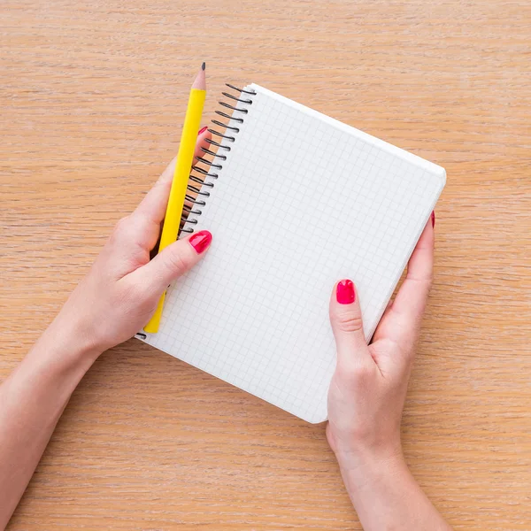 Frauen halten ein neues Notizbuch auf Holzgrund in der Hand — Stockfoto