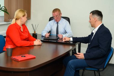 Üç kişilik bir ekip bir ofiste oturup tartışıyorlar.