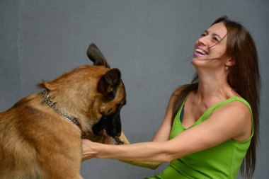 Gri arka planda oynayan esmer bir kadının yakın plan fotoğrafı. Gülüyor.
