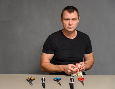 Ciddi bir adam elinde yarayla kameraya bakıyor.