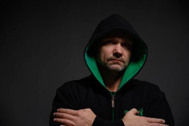 Başlıklı bir adam doğrudan kameraya bakıyor.