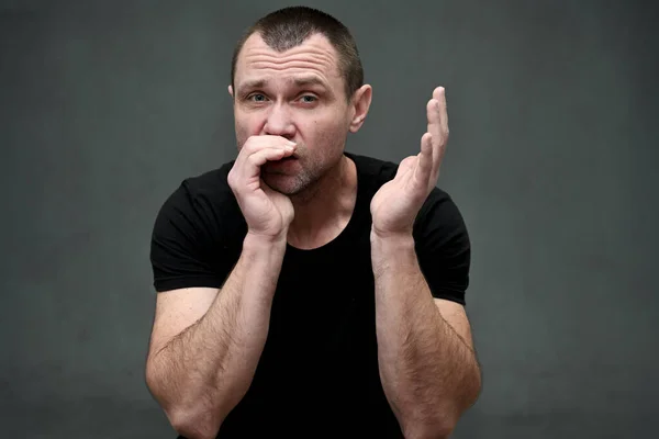 Close-up portrait of a man shouting into his hand on a gray background — Stockfoto