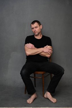 Sakin adamlar sandalyeye oturur. Gri arkaplanda dikey fotoğraf