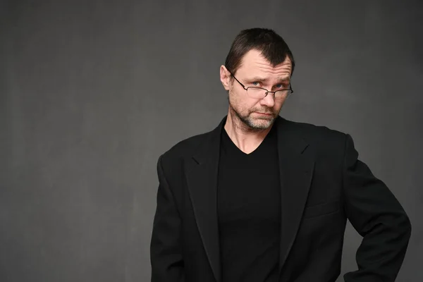 Portret van een volwassen man in bril met ongeloof op een grijze achtergrond — Stockfoto