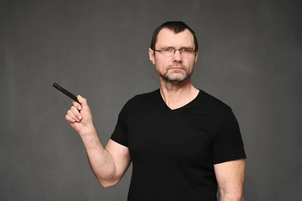 Een volwassen man met een zwart T-shirt en een bril wijst naar de zijkant met een pen — Stockfoto
