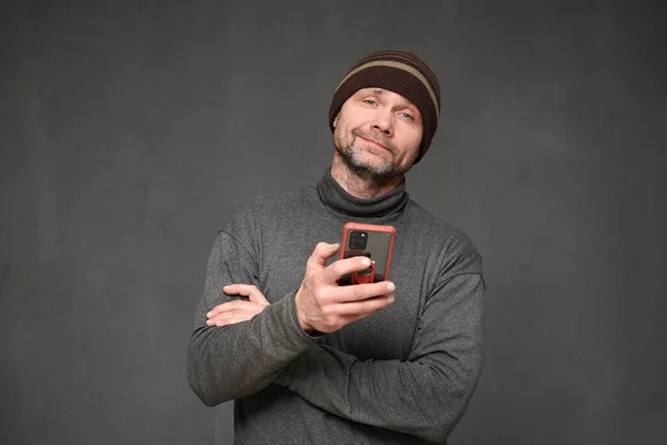 Retrato de un hombre con un teléfono y una sonrisa sobre un fondo gris Fotos de stock libres de derechos